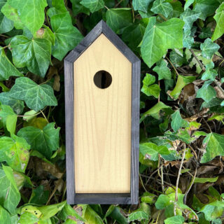 vogel huisje met zwart en goud gekleurd hout in bossage vooraanzicht