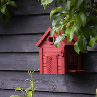 rood design vogel huisje aan zwarte schutting