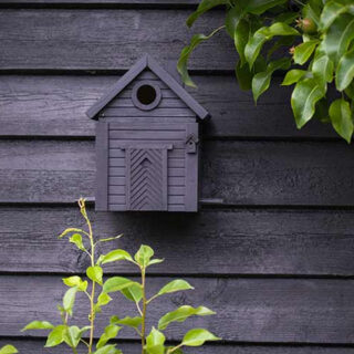 zwarte schutting met zwart design vogelhuisje eraan