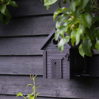 zwarte schutting met zwart design vogelhuisje eraan