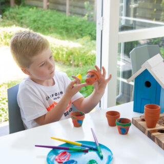 Kind verft kleine potjes met zijn vingers